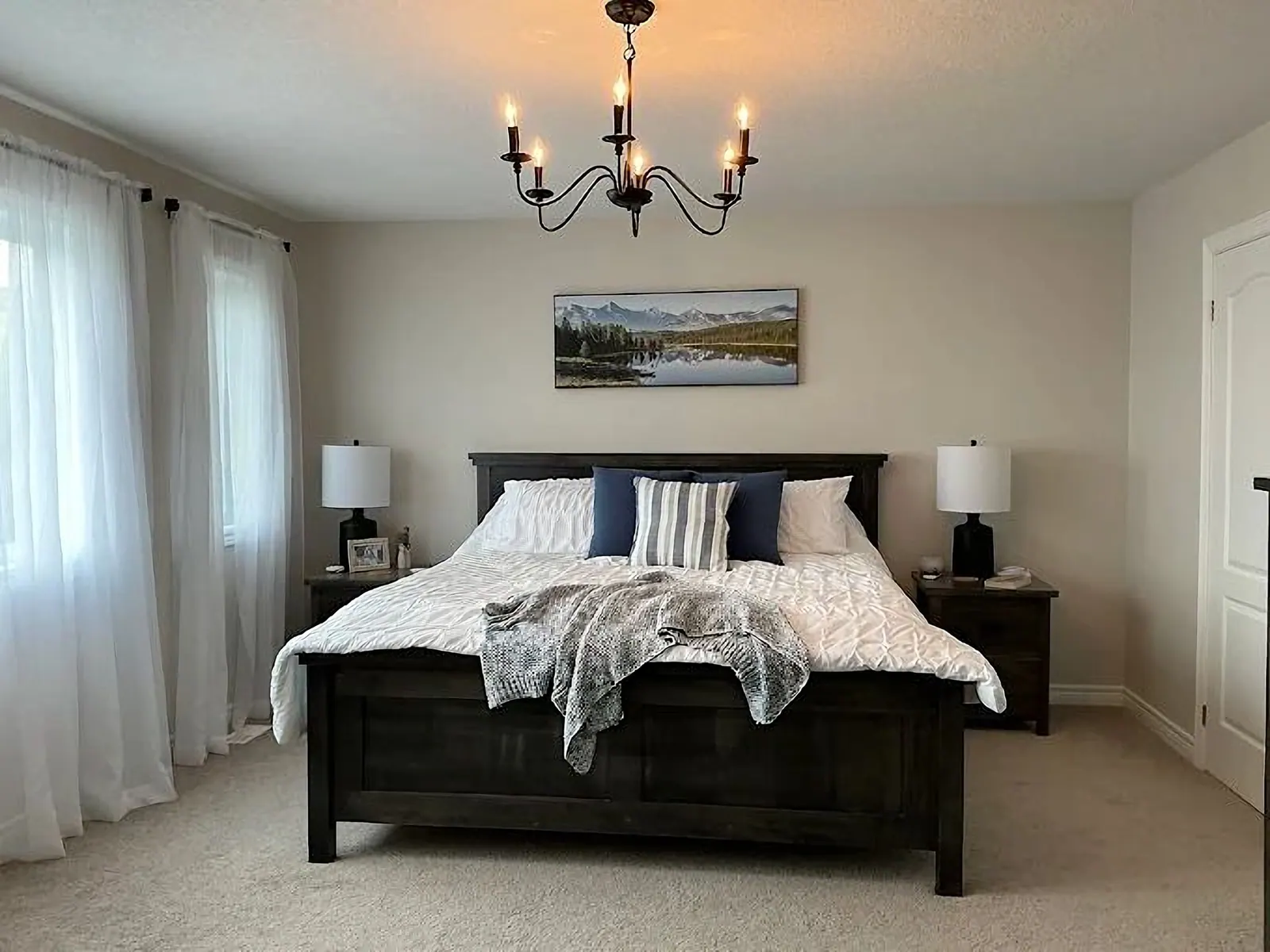 Bedroom with a black chandelier and crisp white drapery