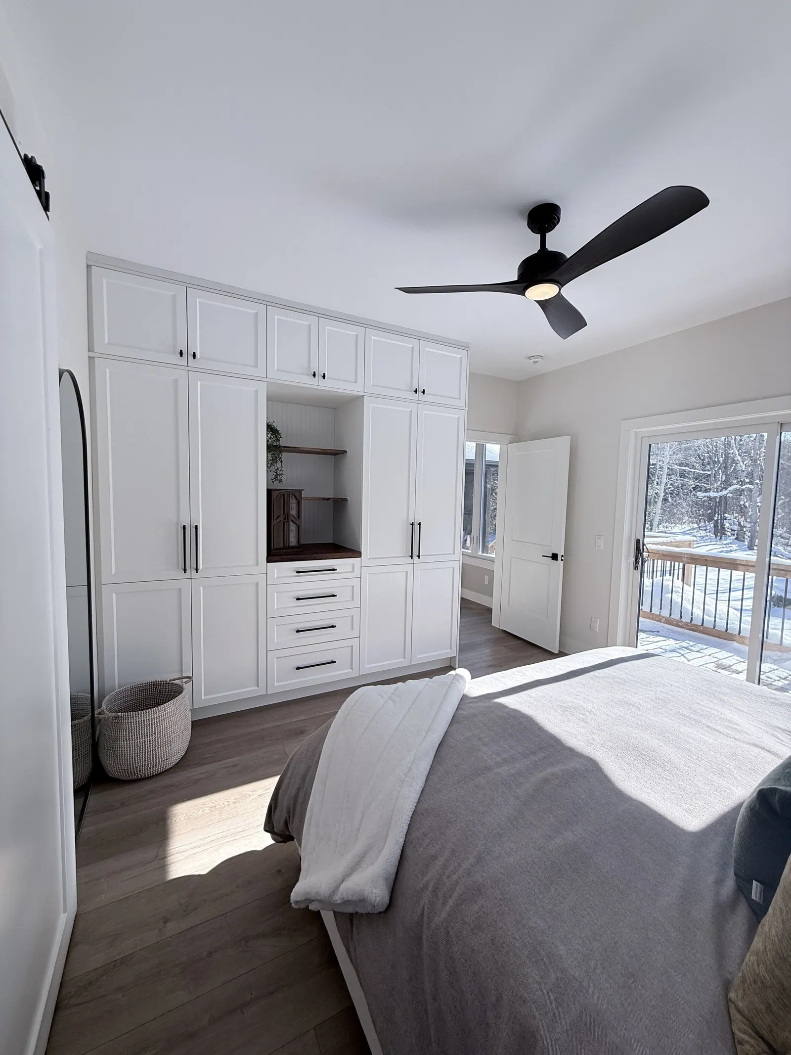 Bedroom with painted white built-in wardrobes and a ceiling fan