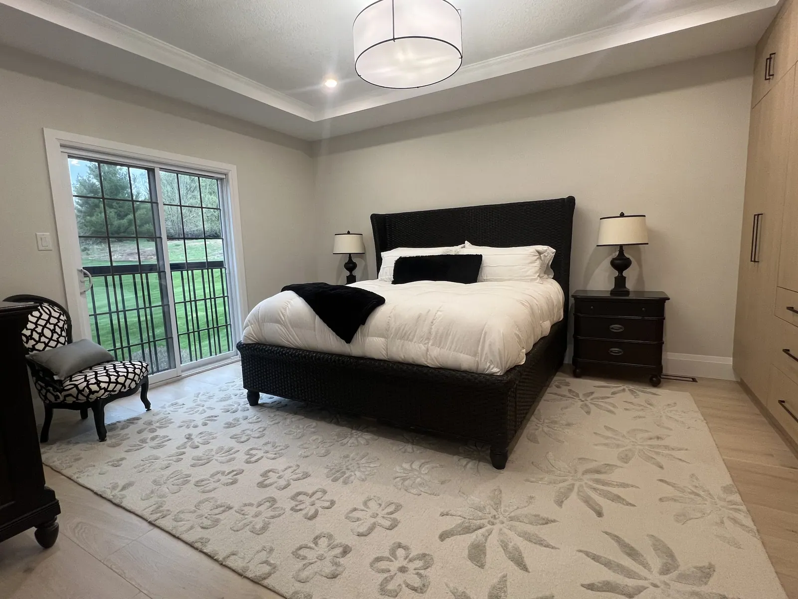 Bedroom with soft grey walls, a dark bed and large windows