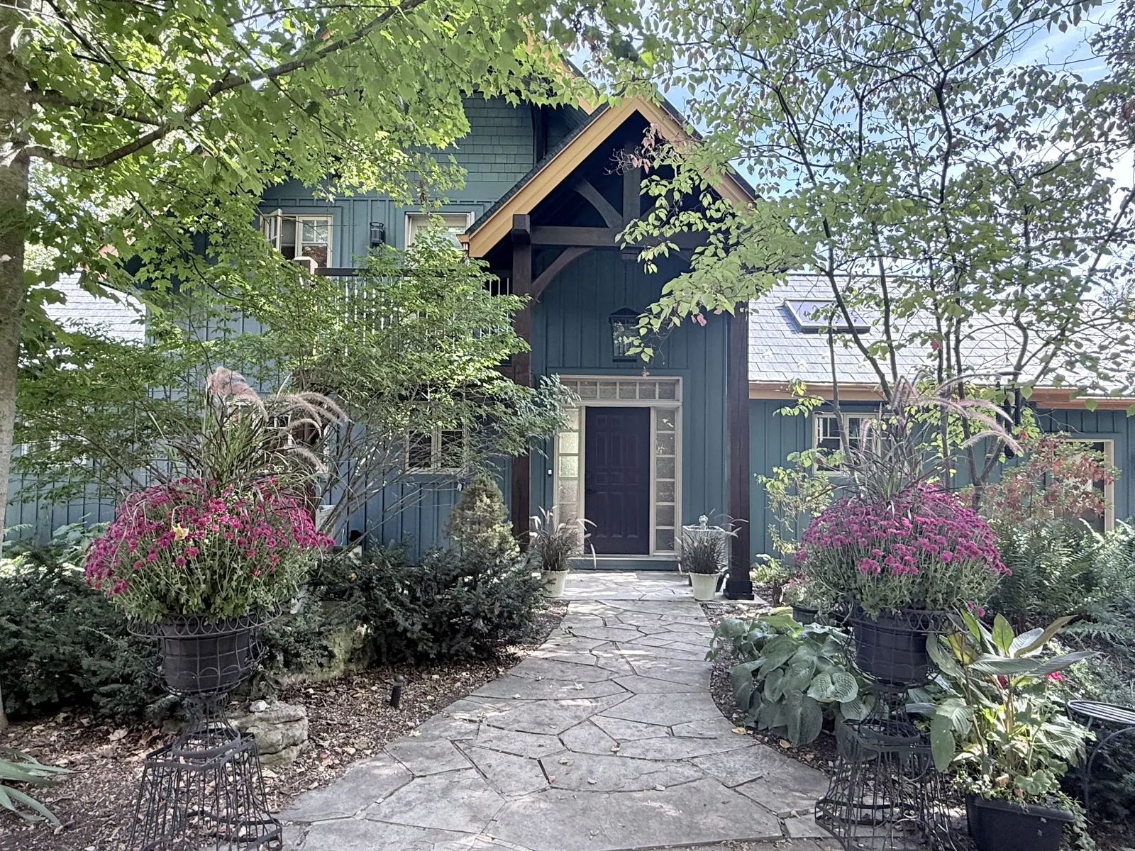 Front entrance of a blue home framed by autumn plantings