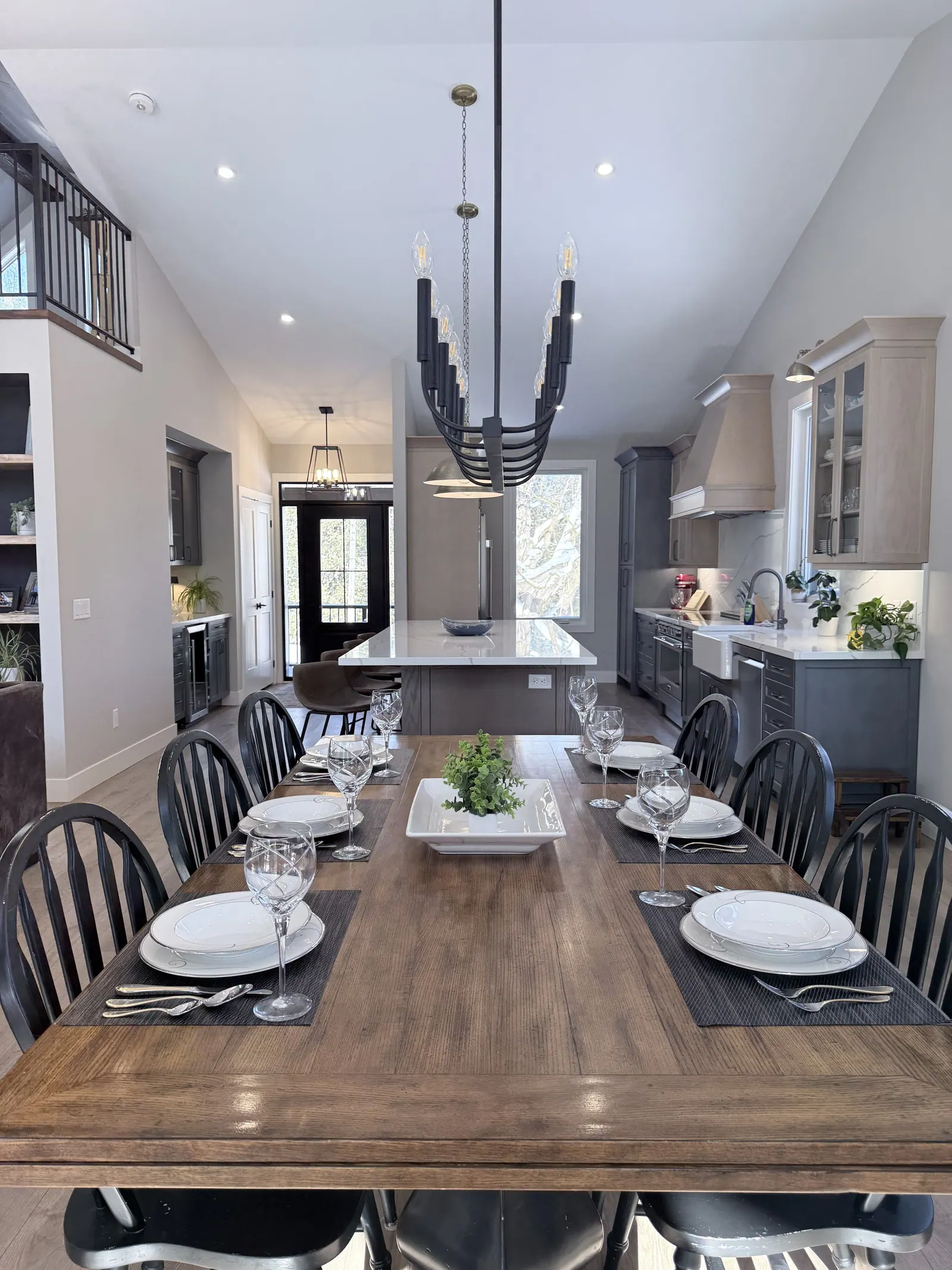 Long dining table set for dinner beside a kitchen island