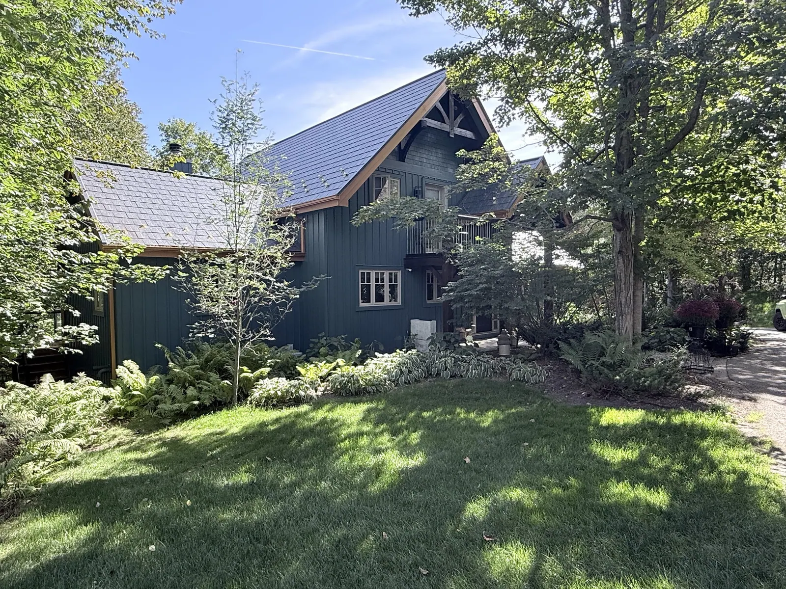Painted cabin with a steel roof among mature trees