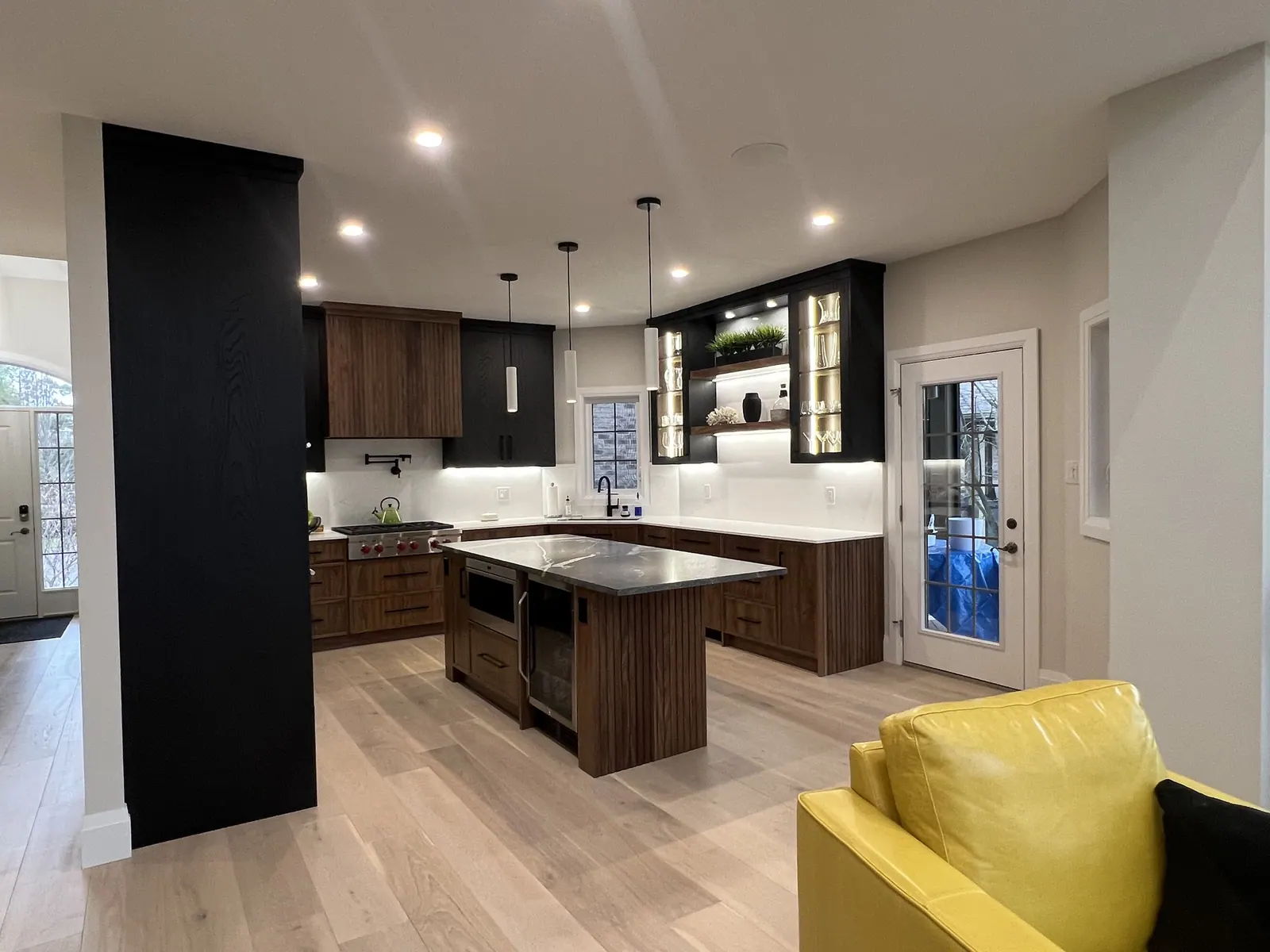 Kitchen with dark cabinets, a wood island and a yellow accent chair
