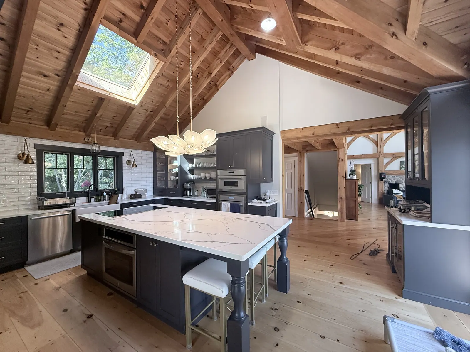 Kitchen with exposed timber beams, dark cabinetry and a quartz island