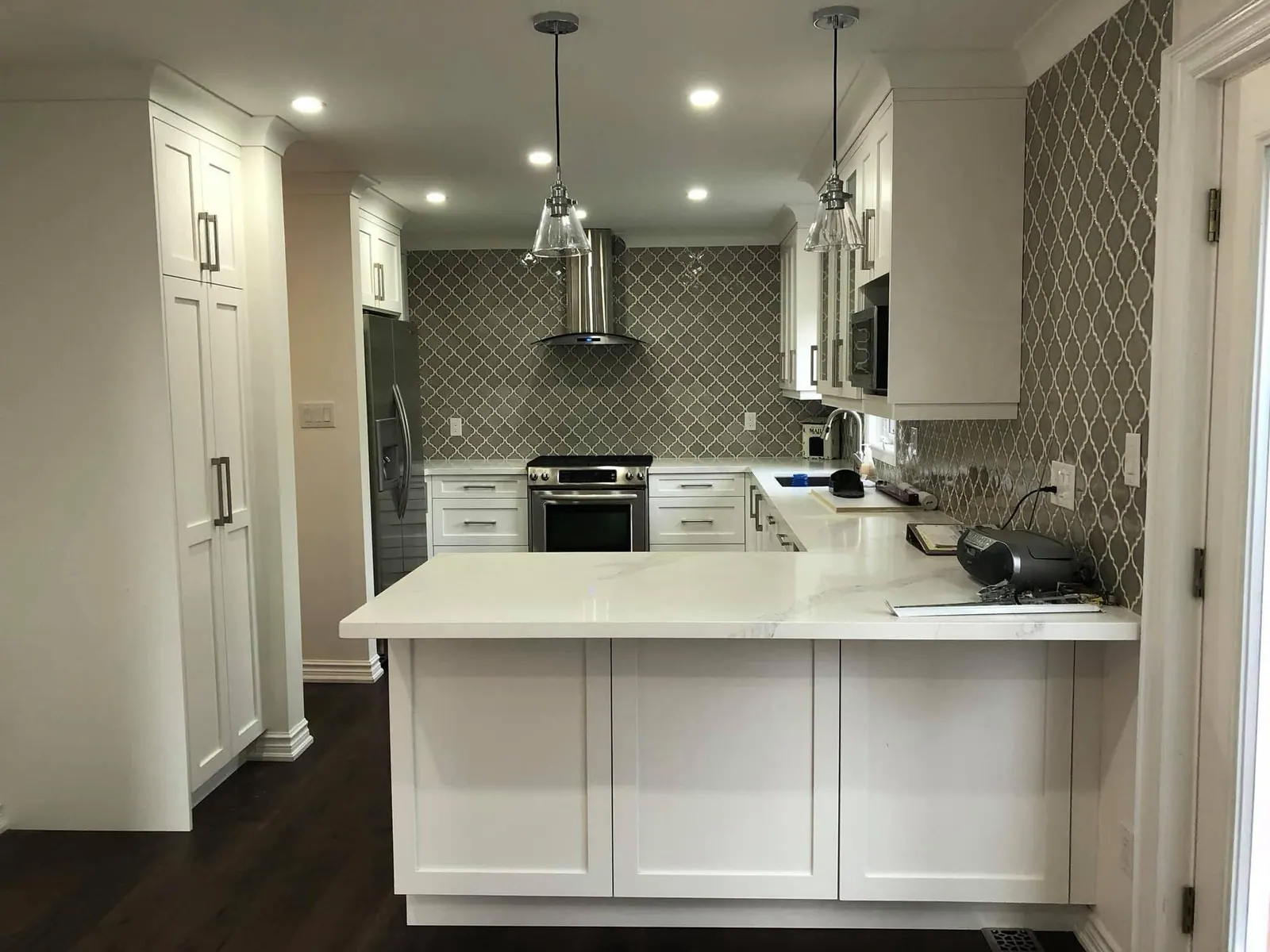 White kitchen with a patterned backsplash and quartz counters