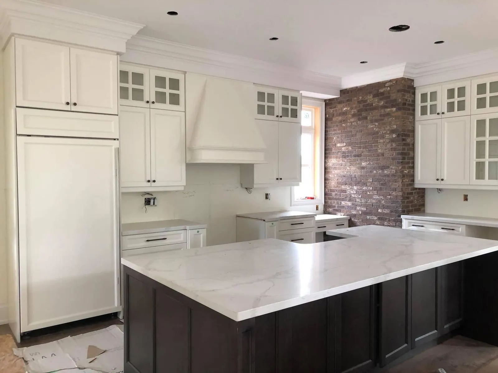 Kitchen with painted white cabinets and a brick accent wall
