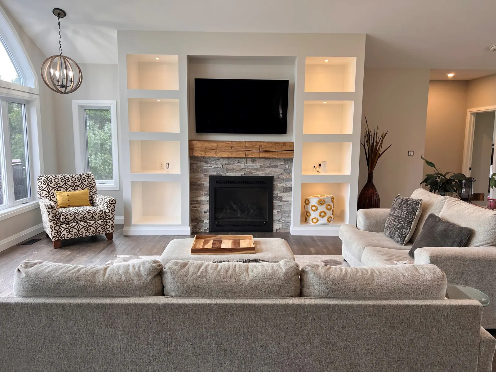 Living room with a stone fireplace and lit built-in shelves