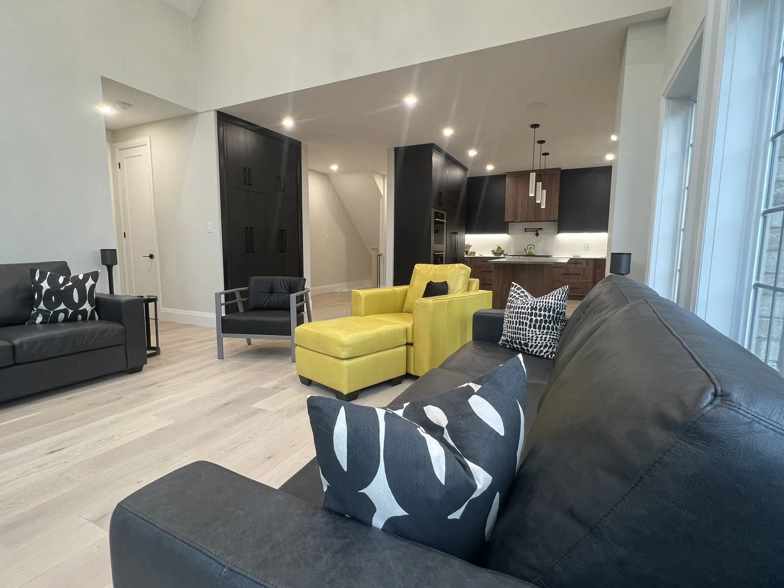 Living room with a charcoal sofa, yellow accent chairs and light wood floors