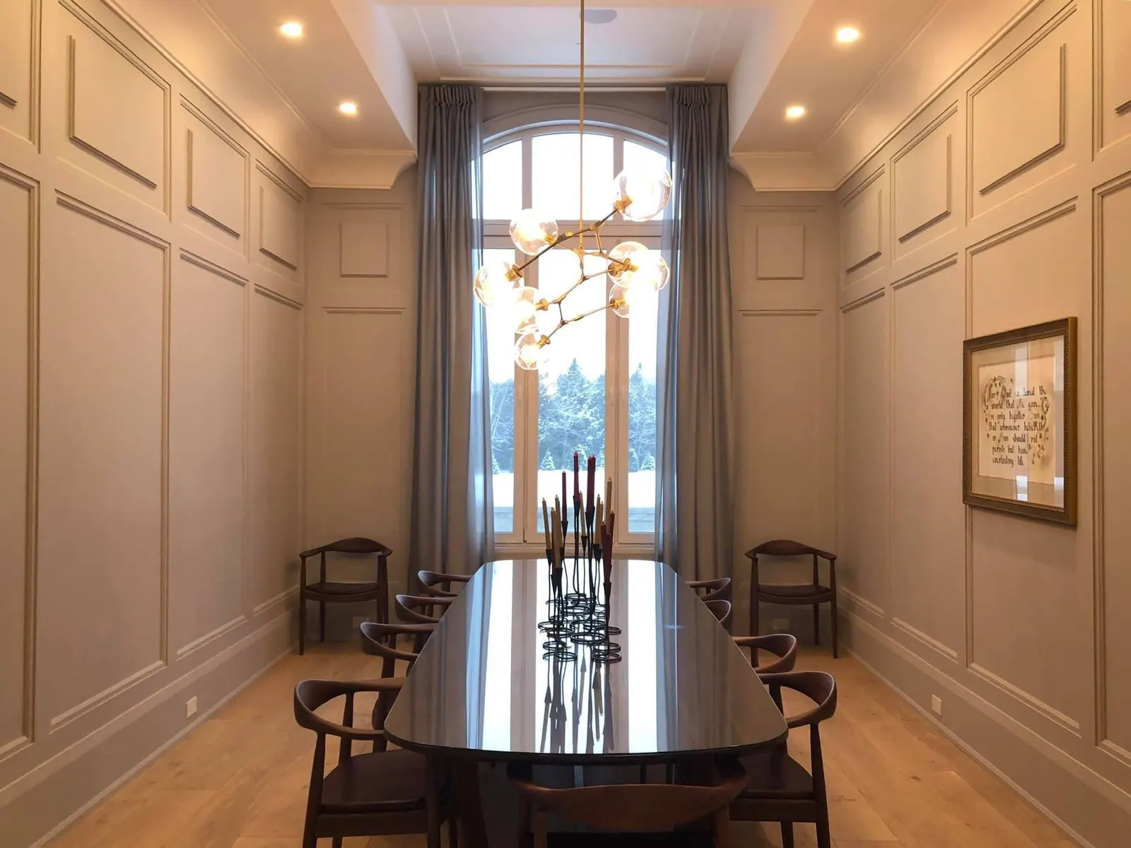 Dining hall with painted wall panelling and a tall arched window