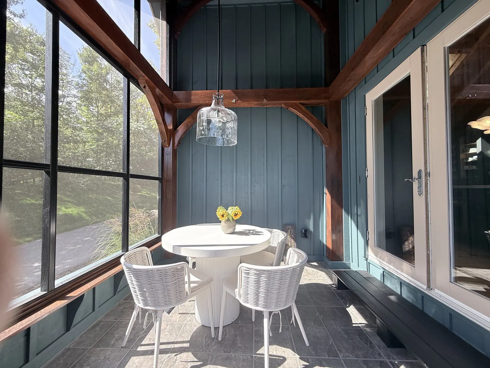 Screened porch with blue panelling and a round dining table